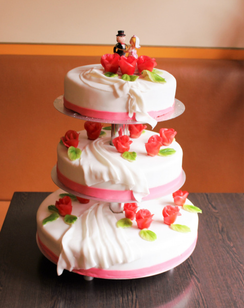 Süße Brautpaarfigur auf dreistöckiger Hochzeitstorte